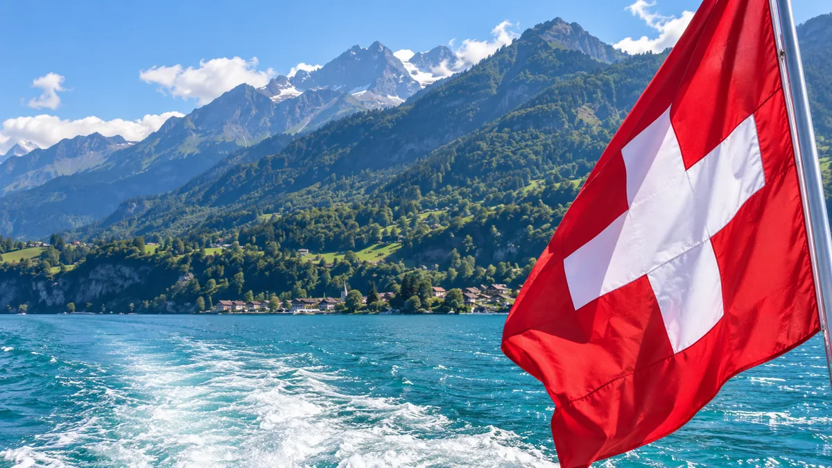 Swiss flag beside an Alpine lake and mountains