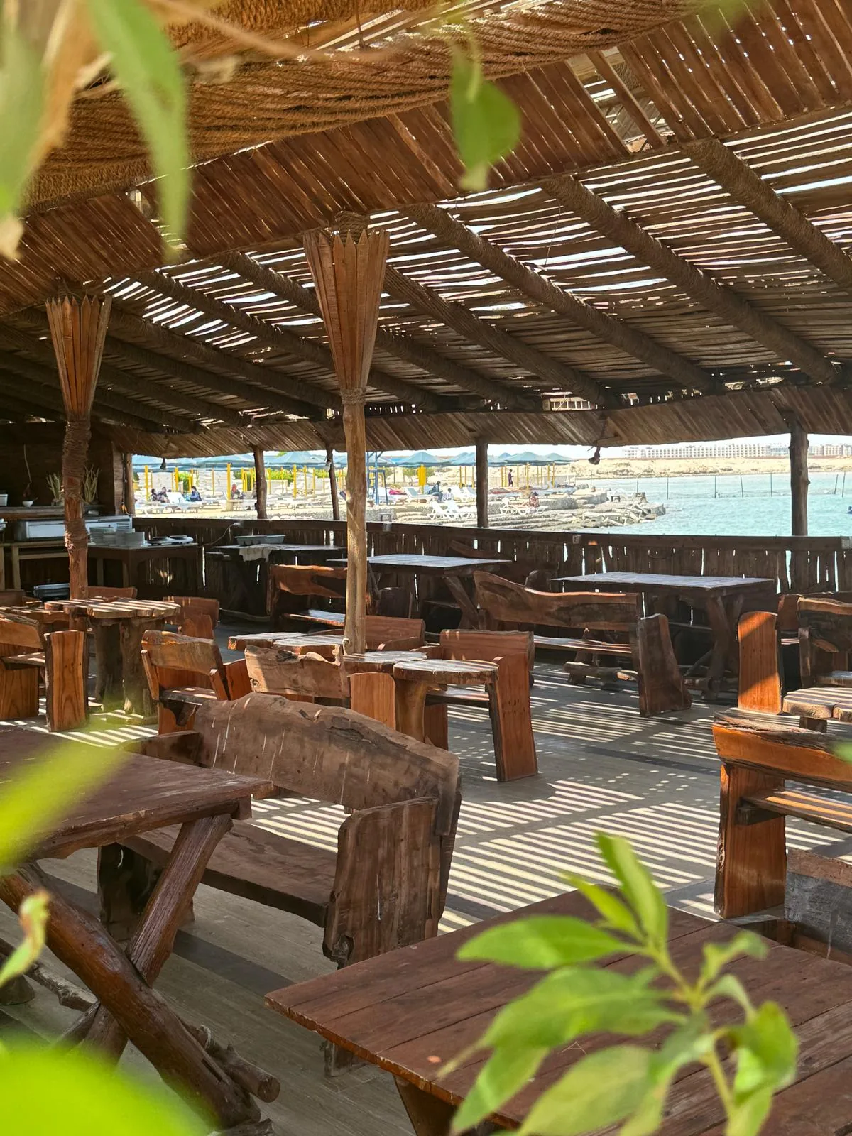 Wooden tables at DaVinci Beach Restaurant overlooking the private beach and Red Sea in Hurghada